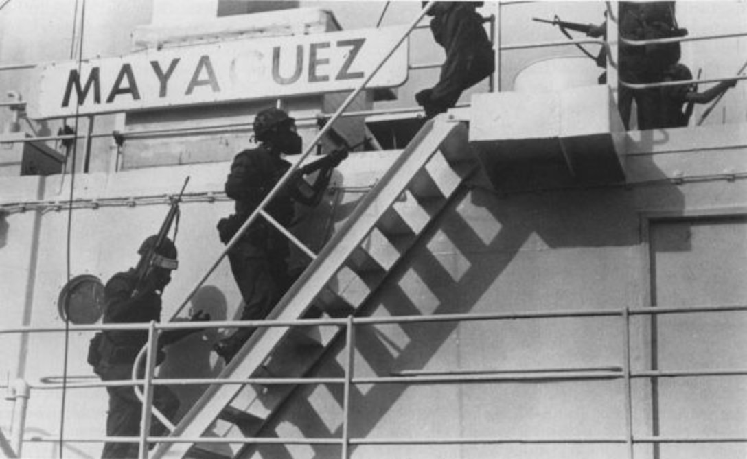 Marines climb stairs on a ship.