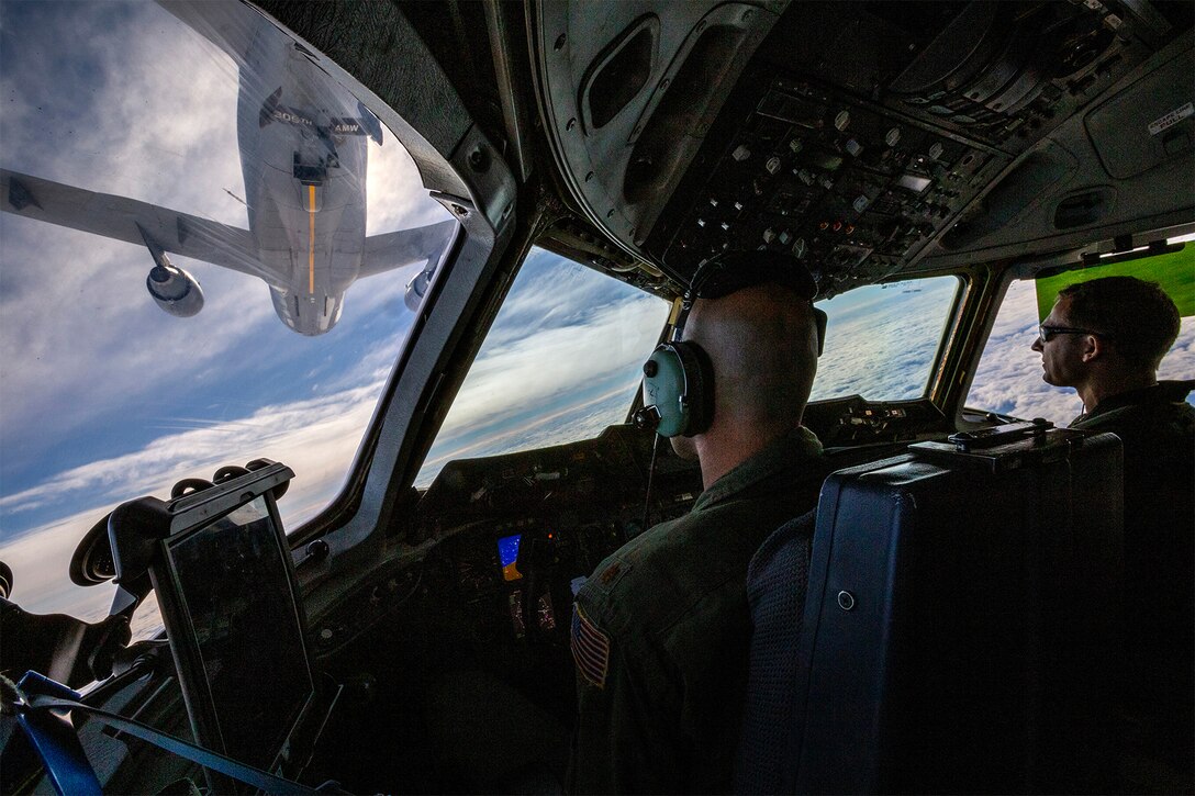 Two pilots fly underneath an aircraft during a training mission.