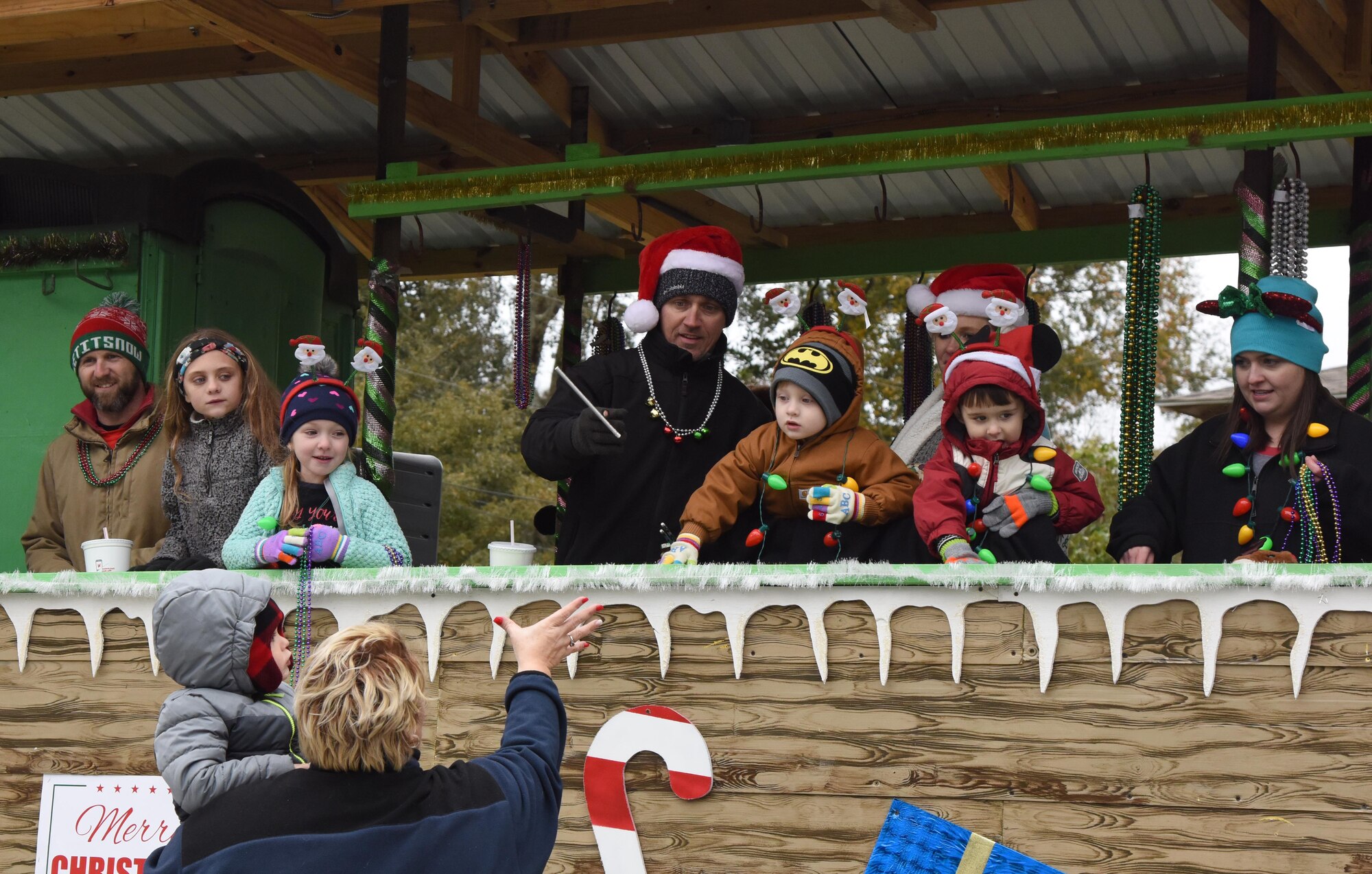 Passengers aboard decorated floats throw toys, candy and beads to families during the Ocean Springs Christmas Parade in Ocean Springs, Mississippi, Dec. 9, 2018. The Keesler Air Force Base Honor Guard and 81st Training Group Airmen participated in the event. (U.S. Air Force photo by Kemberly Groue)