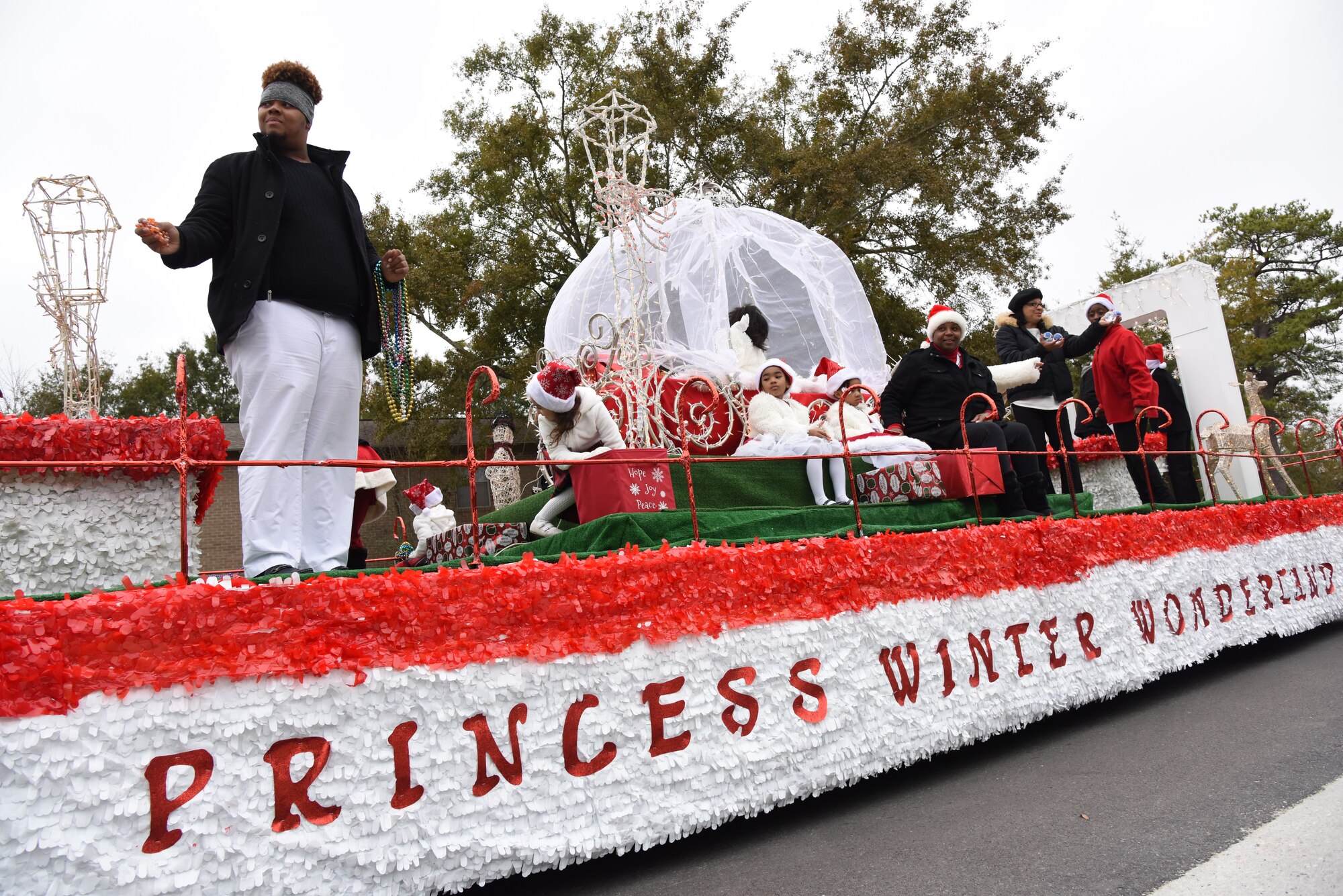 Passengers aboard decorated floats throw toys, candy and beads to families during the Ocean Springs Christmas Parade in Ocean Springs, Mississippi, Dec. 9, 2018. The Keesler Air Force Base Honor Guard and 81st Training Group Airmen participated in the event. (U.S. Air Force photo by Kemberly Groue)