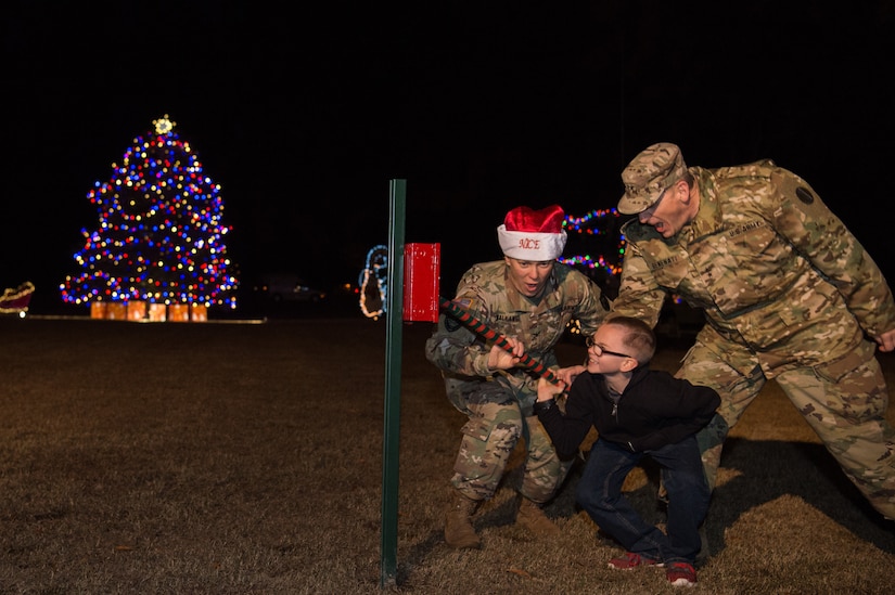 (Right)U.S. Army Maj. Gen. Paul Benenati, U.S. Army Training and Doctrine Command deputy chief of staff, (left) U.S. Army Col. Jennifer Walkawicz, 733rd Mission Support Group commander, and (middle) Trevor Horacek, son of U.S. Army Pfc. Andrew Horacek, 149th Seaport Operation Company, 10th Battalion, 7th Transportation Brigade (Expeditionary) cargo specialist, pull a lever to light the tree during the Holiday Tree Lighting ceremony at Fort Eustis, Virginia, Dec. 7, 2018.