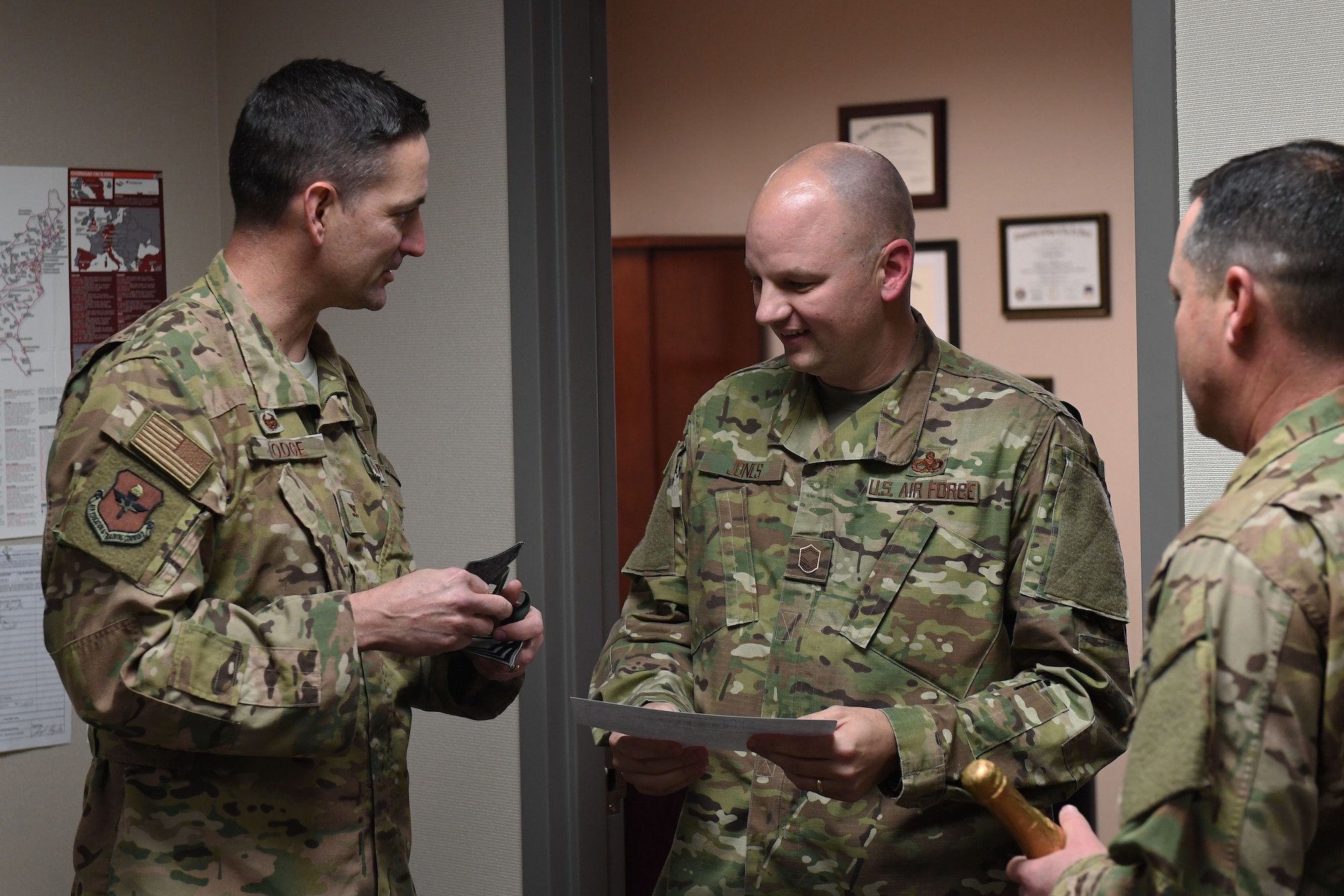 Three white men in camouflage uniforms talk about promotion to chief in the US Air Force.