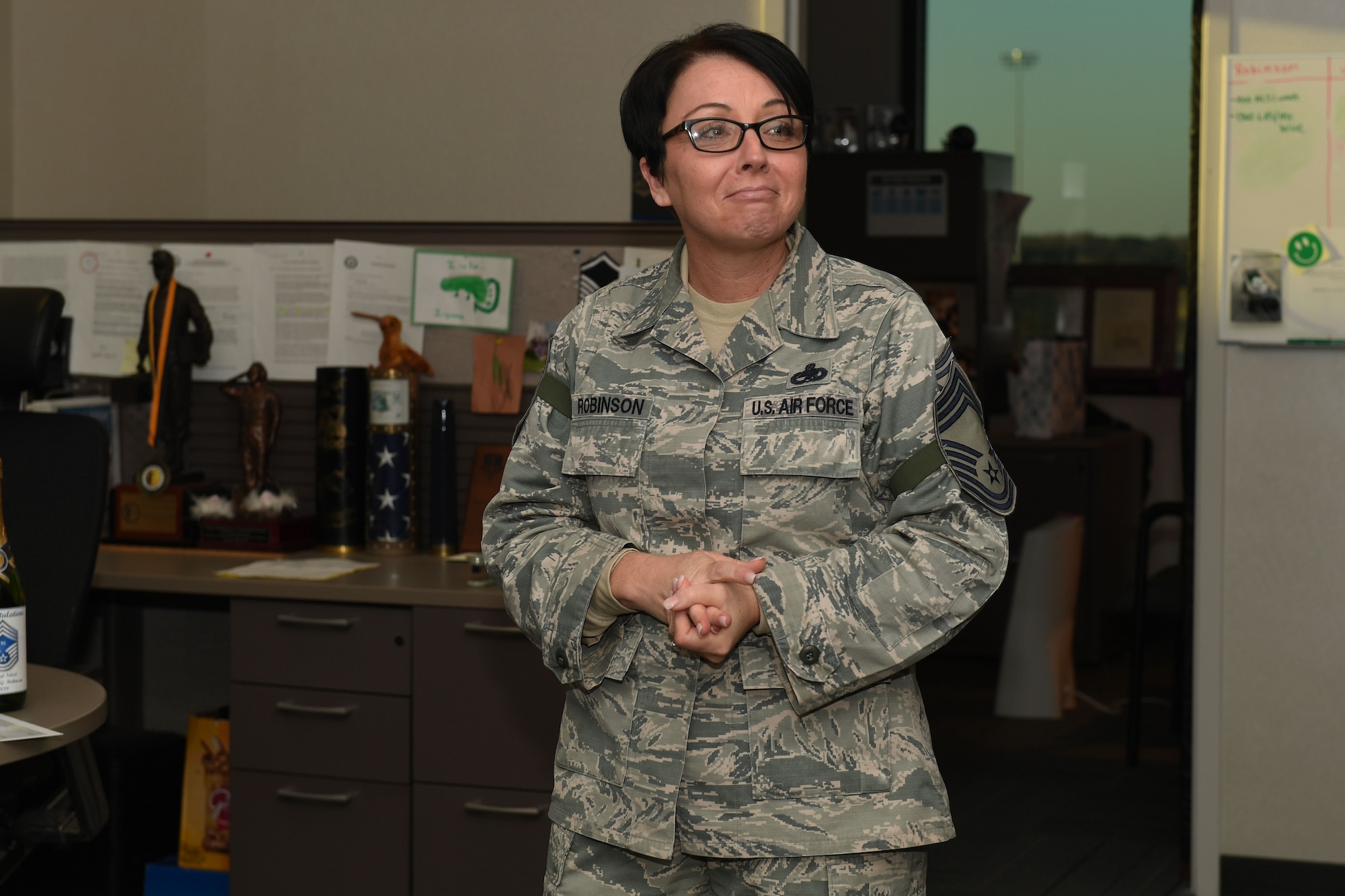 A white female in camouflage looks off photo at airmen.