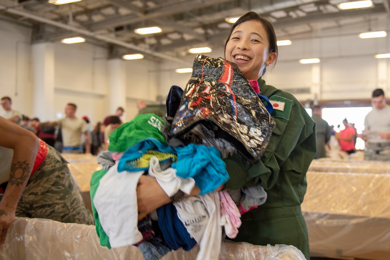 A Japan Air Self-Defense Force member puts clothing into an air bundle.