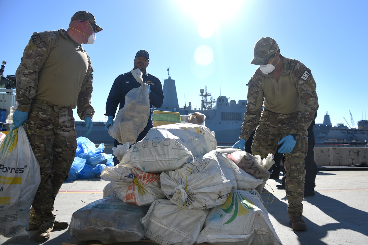 Troops work around sacks on a pier.