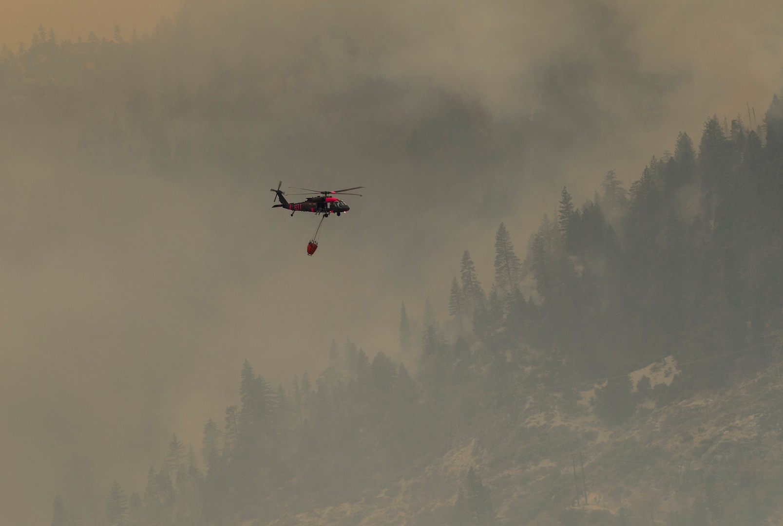 A U.S. Army UH-60M Black Hawk helicopter assigned to the 1st Assault Helicopter Battalion, 140th Aviation Regiment, California Army National Guard, flies through the smoky Feather River Canyon while helping authorities contain the northeastern edge of the Camp Fire in Butte County, California, Nov. 16, 2018. The Cal Guard provided four helicopters, including two of its new M-models, to help state agencies contain the deadly fire.