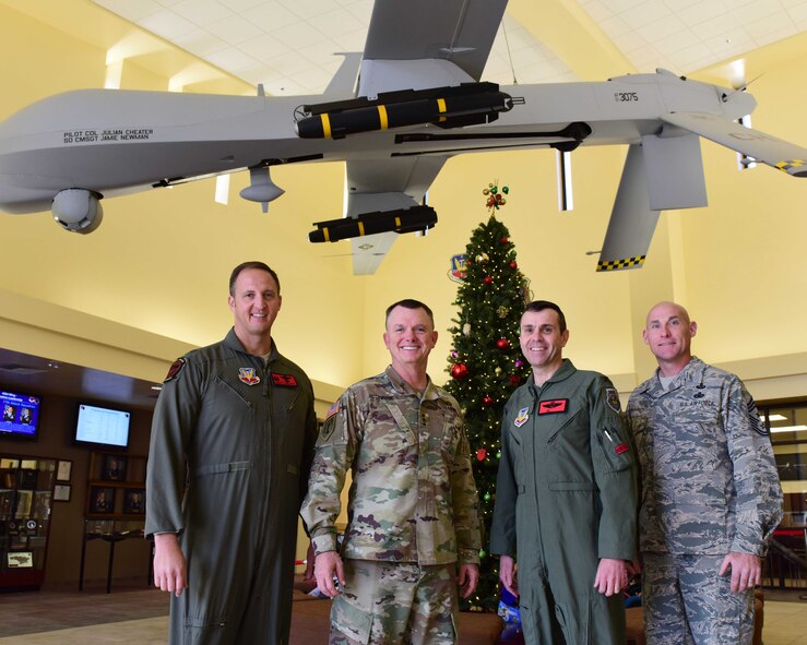 U.S. Air Force Col. Julian Cheater, 432nd Wing/432nd Air Expeditionary Wing commander (left), U.S. Army Lt. Gen. Paul Funk, III Armored Corps and Fort Hood, Texas, commanding general (second from the left), U.S. Air Force Col. Jim,  432nd  WG/432nd AEW vice commander (second from the right), and Chief Master Sgt. Jamie, 432nd  WG/432nd AEW command chief (right), stand under an MQ-1 Predator at Creech Air Force Base, Nevada, Dec. 10, 2018. Funk made a visit to Creech to thank the Remotely Piloted Aircraft Airmen who kept the Soldiers he led safe during Operation Inherent Resolve. (U.S. Air Force Photo by Airman 1st Class Haley Stevens)