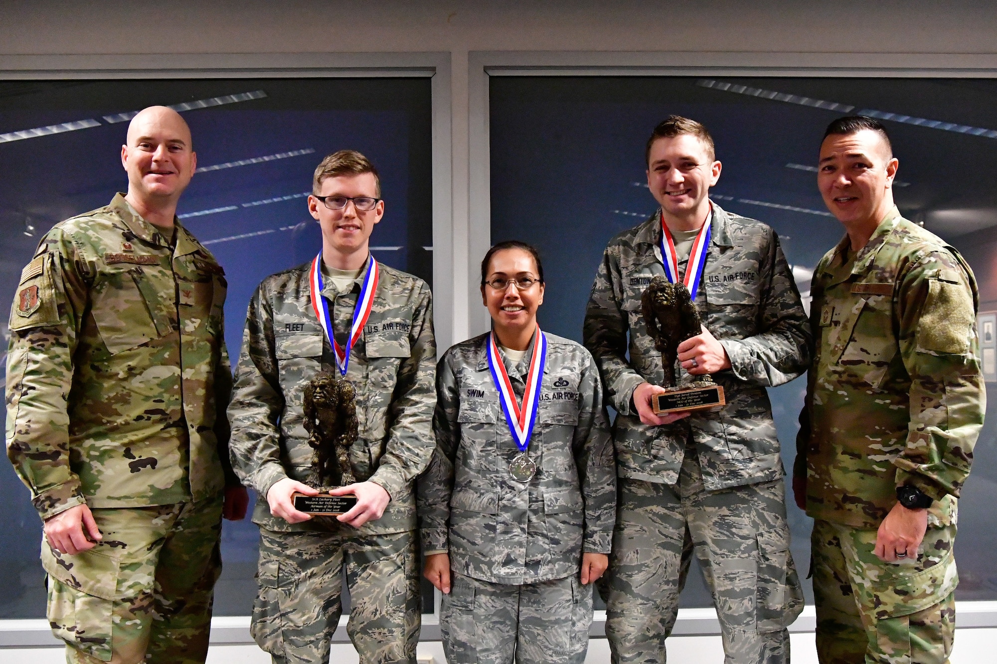 The 225th Air Defense Squadron annual award winners pose with their Bigfoot trophies and medals Dec. 1, 2018 on Joint Base Lewis-McChord, Washington. Pictured from left to right are:  Col. Brett Bosselmann, 225th ADS commander; Airman of the Year Senior Airman Zachary Fleet, interface control technician;  SNCO of the Year Senior Master Sgt. Julietta Swin, superintendent of data link operations; NCO of the Year Staff Sgt. Jared Denton, NCOIC of surveillance training. Not pictured is: CGO of the Year Capt. Marvin Yamada, weapons flight commander.  (U.S. Air National Guard photo by Maj. Kimberly D. Burke)