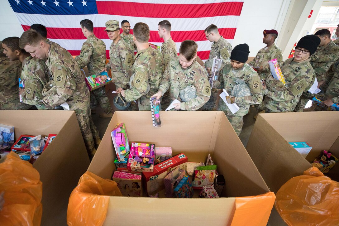 Soldiers drop toys into large cardboard boxes.