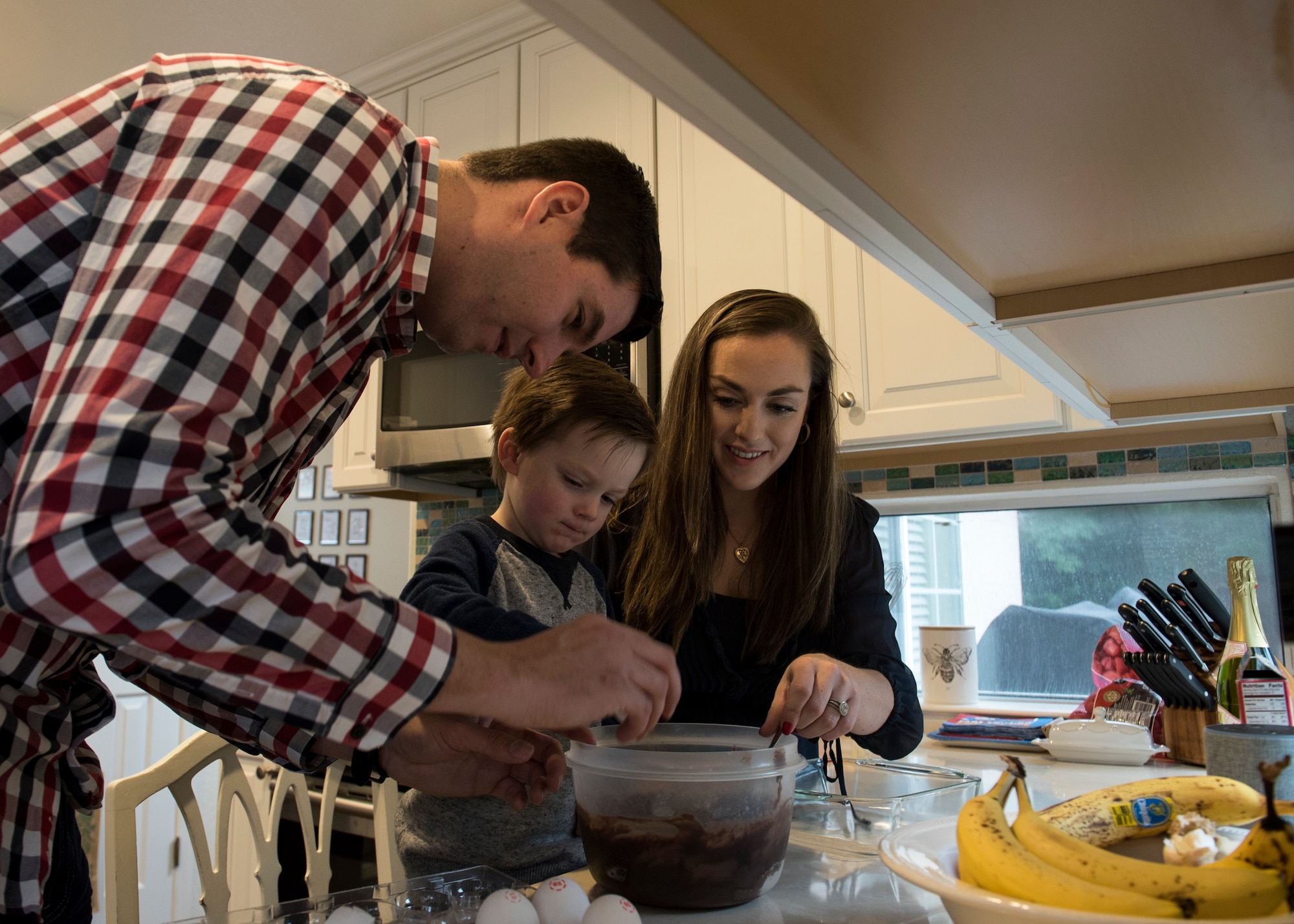 Capt. Steven Noller, 21st Airlift Squadron pilot, his spouse Morgan and their son Camden, prep a cake for baking in their home in Vacaville, California, Dec. 7, 2018. Morgan won the 2018 Joan Orr Air Force Spouse of the Year Award. (U.S. Air Force photo by Lan Kim)