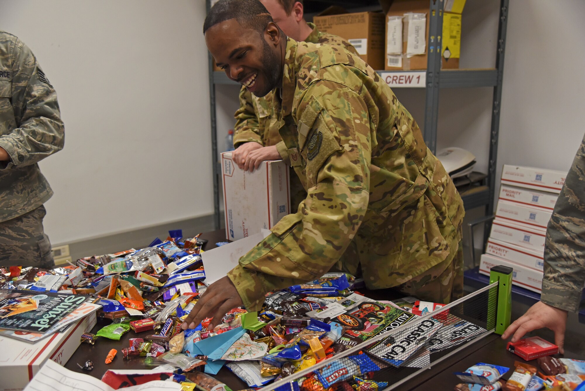Tech. Sgt. Jonathan Rogers, 93 Air Refueling Squadron boom operator, opens a Treats 2 Troops care package Dec. 4, 2018, at Morón Air Base, Spain. For over a month leading up to the annual Treats 2 Troops packing event at Fairchild Air Force Base, Washington, thousands of items are collected from the Inland Northwest Community including candy, snacks, lip balm, office supplies and toiletries. Local schools in the area also contribute to the creation of care packages by making handmade holiday cards. (U.S. Air Force photo/Staff Sgt. Mackenzie Mendez)