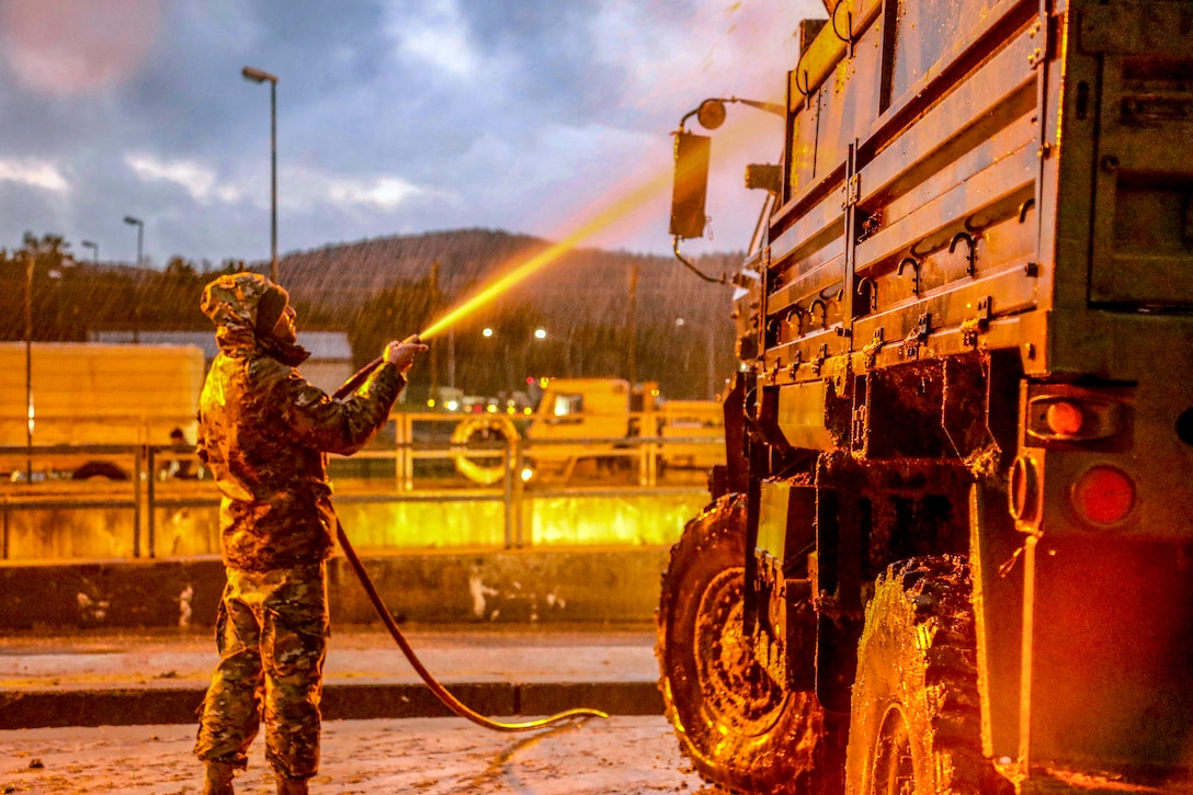 A soldier sprays a truck down.