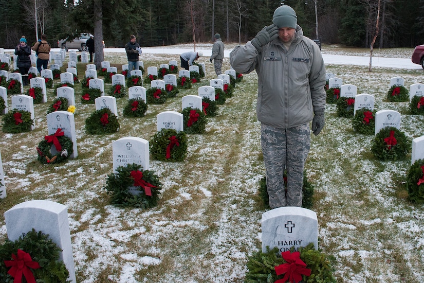 An Airman salutes after placing wreath on a grave at Arlington National Cemetery.