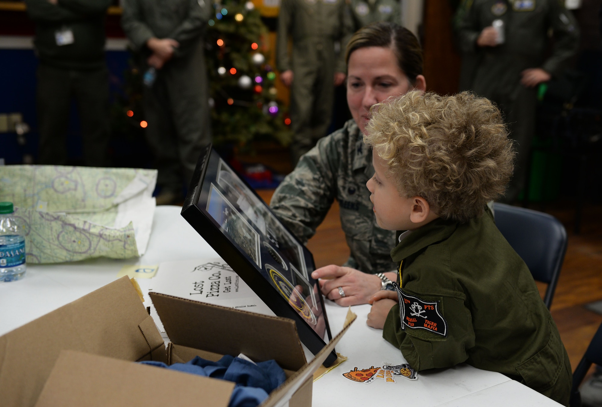 Tobias Taylor, Pilot for a Day, looks at a plaque of his hero shot and coin commemorating his time on base with Col. Samantha Weeks, 14th Flying Training Wing commander, Dec. 6, 2018, on Columbus Air Force Base, Mississippi. Weeks presented the plaque during lunch, thanking Tobias and his family for visiting Columbus AFB. (U.S. Air Force photo by Airman Hannah Bean)