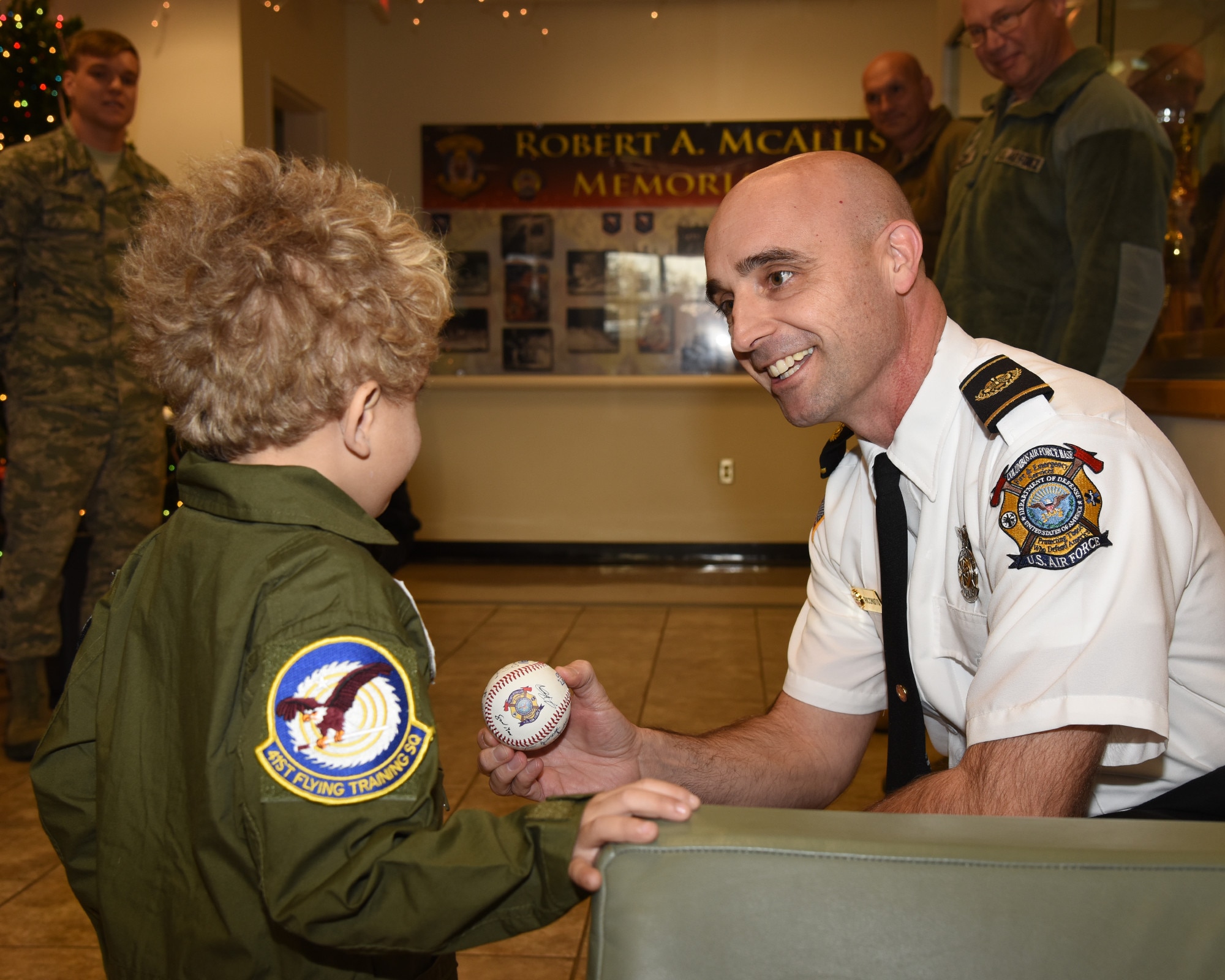 Shawn Ricchuito, 14th Civil Engineer Squadron Fire Chief, presents Tobias Taylor, Pilot for a Day, a baseball signed by all members of the fire department, Dec. 6, 2018, on Columbus Air Force Base, Mississippi. Tobias and his family enjoyed many aspects of Columbus AFB including a personalized tour of the fire department, time in the T-6 flight simulator, and more. (U.S. Air Force photo by Melissa Doublin)