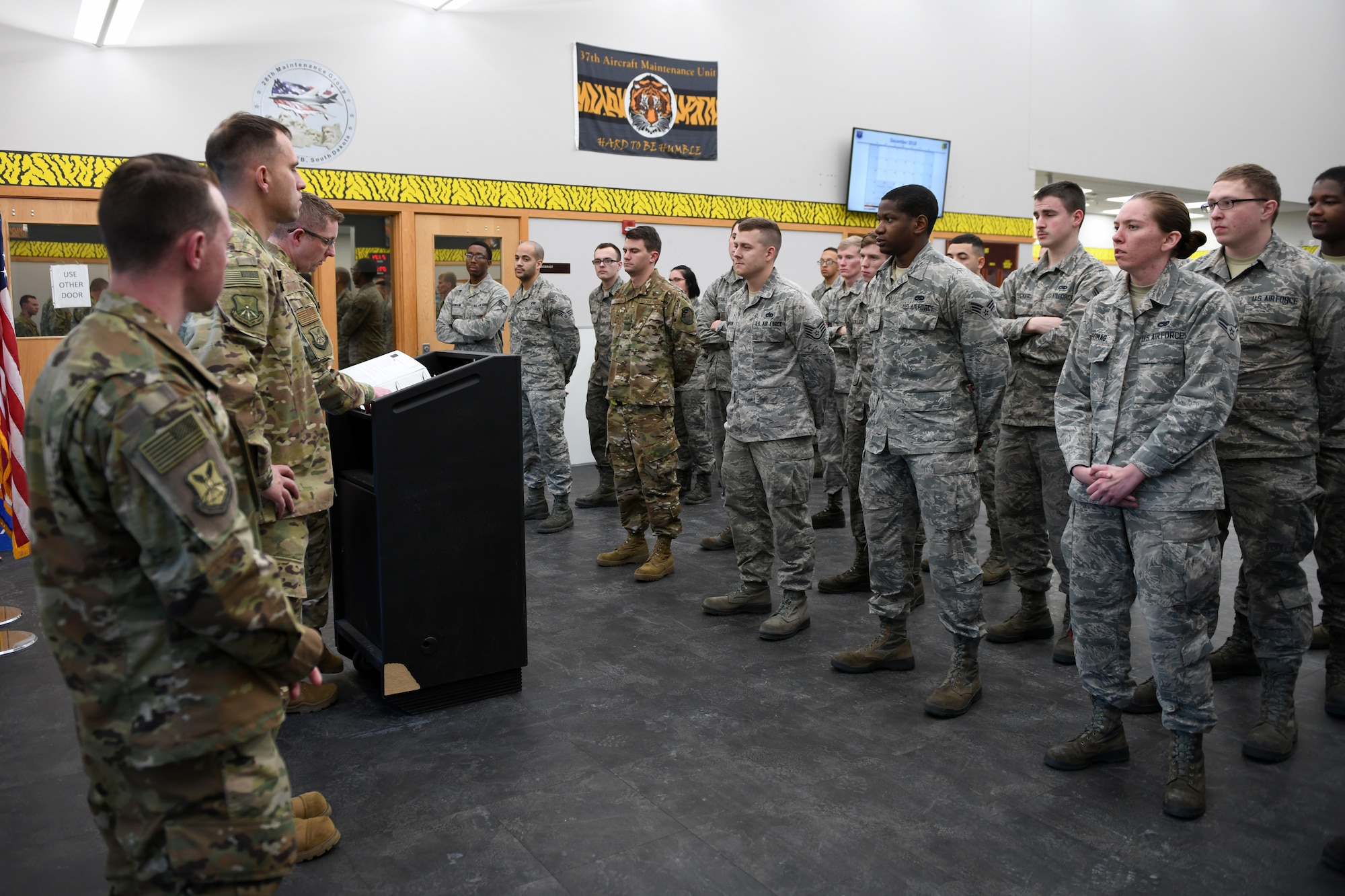 Airmen from the 28th Aircraft Maintenance Squadron receive a briefing during their roll call at shift change on Ellsworth Air Force Base, S.D., Dec. 4, 2018. During shift change, the Airmen are briefed on current weather conditions and different events going on around the squadron. (U.S. Air Force photo by Senior Airman Denise Jenson