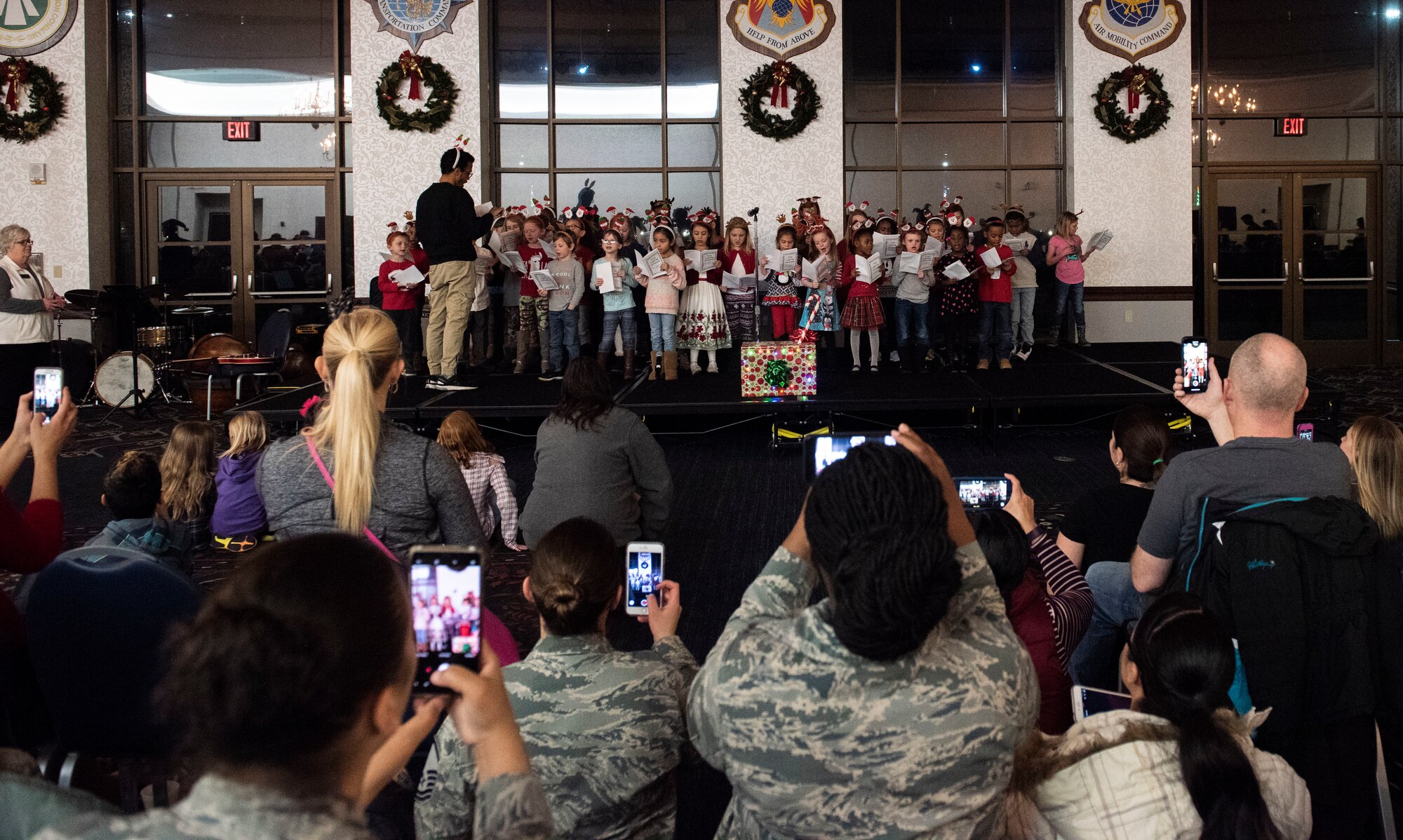 Parents crowd to take photos of the Scott Youth Center choir as they perform their holiday concert during the Holiday Party and Tree Lighting Ceremony, Dec. 7, 2018, at Scott Air Force Base, Illinois. On-base and off-base organizations coordinated to pull of the event.