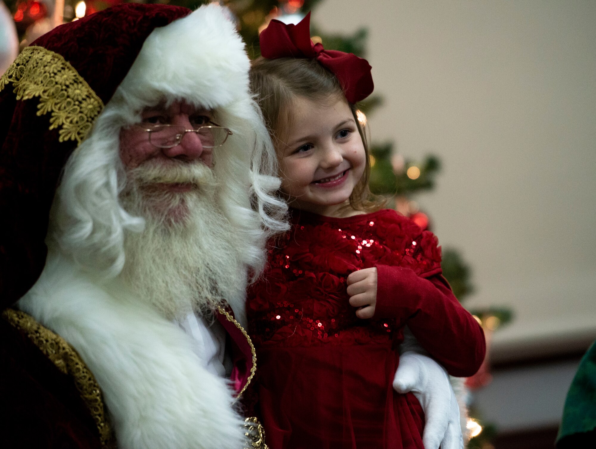 Santa and a young member of Team Scott sit for a photo during the Holiday Party and Tree Lighting Ceremony, Dec. 7, 2018, at Scott Air Force Base, Illinois. During the event, the non-profit organization Trees for Troops provided free Christmas trees to families around base, ensuring all young Airmen and families of deployed service members were able to decorate for the holidays.