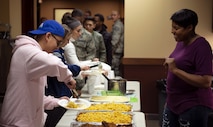 Tech. Sgt. Aisha Terry, 375th Security Forces Squadron NCO in-charge of the Visitor Control Center, greets Airmen during a weekly dorm dinner Dec. 11, 2018, held at the Belleville Dorm Dayroom on Scott Air Force Base, Illinois. The 375th Air Mobility Wing chapel staff manages a weekly “dorm dinner” program that allows organizations to provide home cooked dinners for Airmen.  Along with yummy meals, the effort gets them out of the dorms to socialize and interact with each other and many members of the community both on and off base.