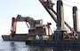 The mechanical dredge NEW YORK, owned and operated by Great Lakes Dredge & Dock Company, removes rock material from the Delaware River as part of the project to deepen the channel from 40 to 45 feet. The project is a joint effort between USACE and the Port of Philadelphia. The deeper channel will provide for more efficient transportation of cargo to and from Delaware River ports.