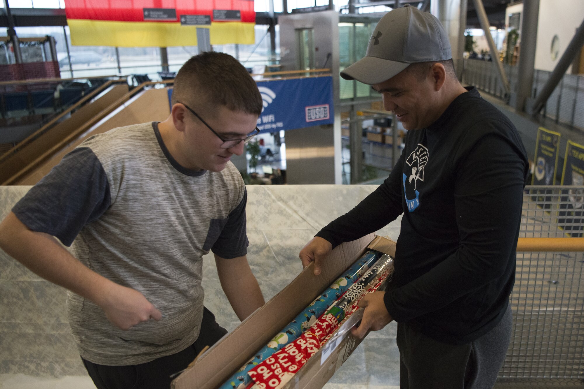 U.S. Air Force Airman 1st Class Michael Tart, left, and Staff Sgt. Anthony Marquez, right, 450th Intelligence Squadron Airmen, decorate the passenger terminal on Ramstein Air Base, Germany, Dec. 7, 2018. The 450th IS hosted a volunteer day as a way for the squadron to give back to non-profit organizations around Ramstein Air Base. (U.S. Air Force Photo by Airman 1st Class Noah Coger)