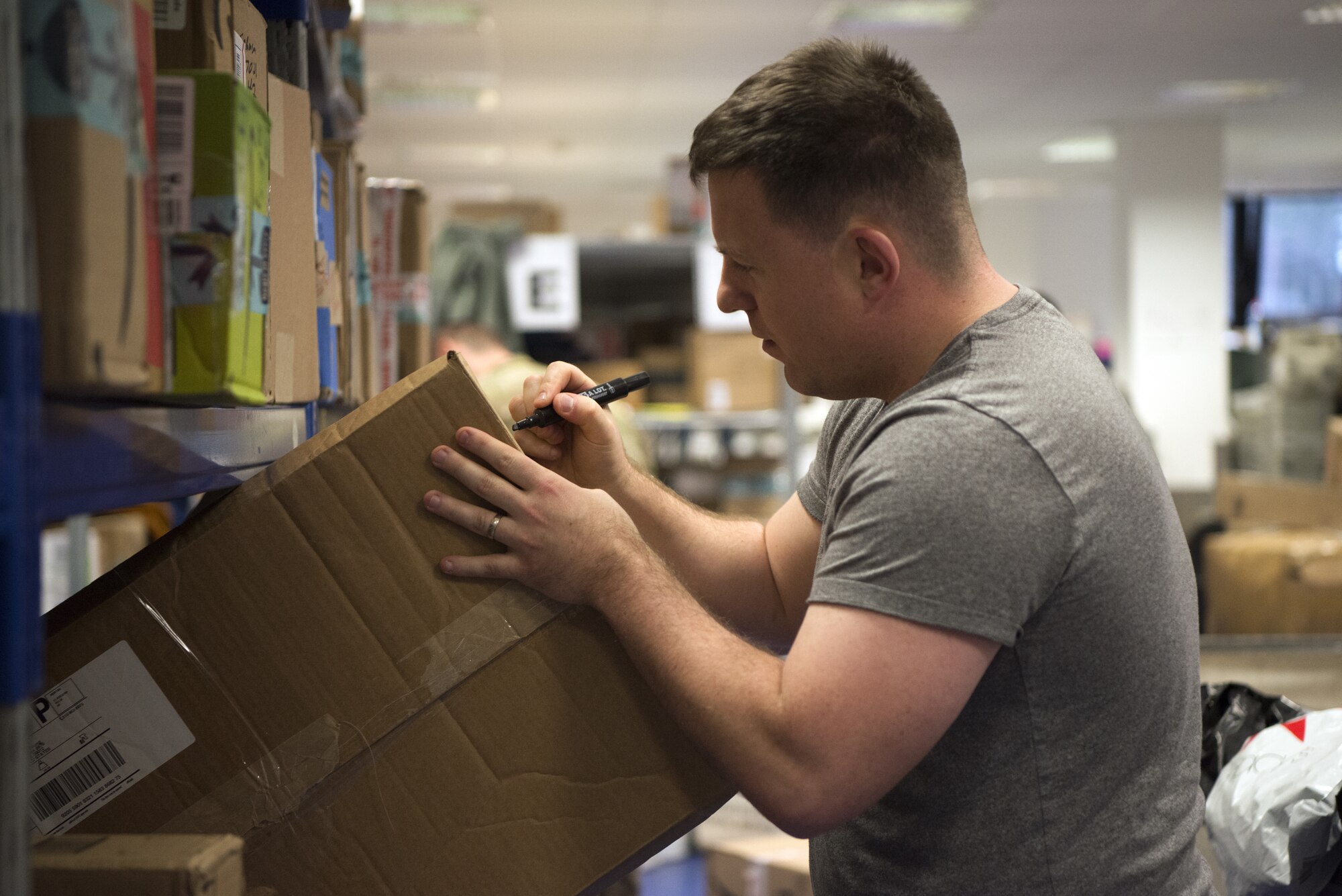 U.S. Air Force Tech. Sgt. Luke Johnson, a member of the 450th Intelligence Squadron, helps sort packages at the North Side Post Office on Ramstein Air Base, Germany, Dec. 7, 2018. The 450th IS hosted a volunteer day as a way for the squadron to give back to non-profit organizations around Ramstein Air Base. (U.S. Air Force Photo by Airman 1st Class Noah Coger)