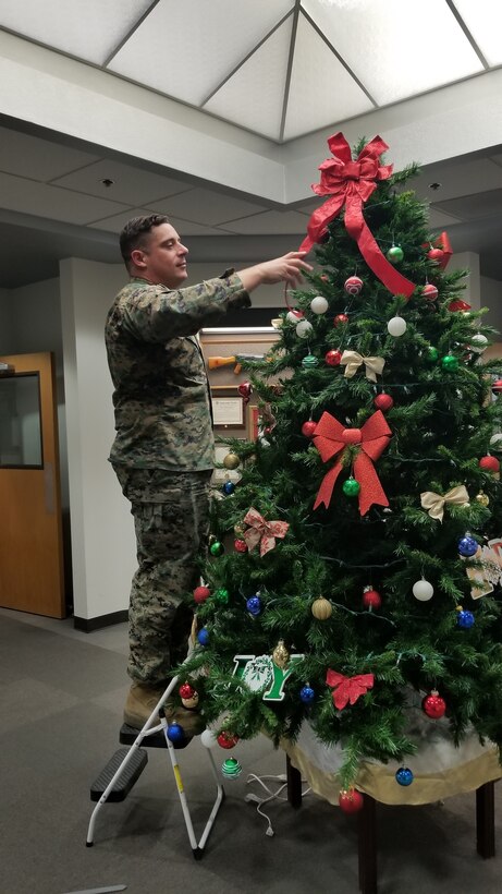 Staff Sgt. Nicholas Hensley, Base Operations Chief, adds the final touch to the Christmas Tree located in Base Headquarters aboard Marine Corps Logistics Base Barstow, Calif., Dec. 6.