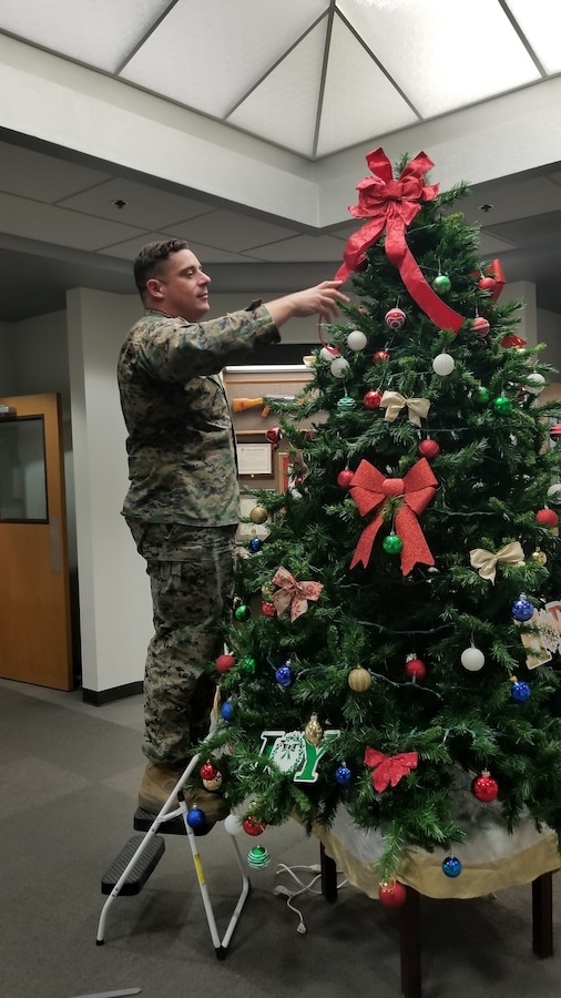 Staff Sgt. Nicholas Hensley, Base Operations Chief, adds the final touch to the Christmas Tree located in Base Headquarters aboard Marine Corps Logistics Base Barstow, Calif., Dec. 6.