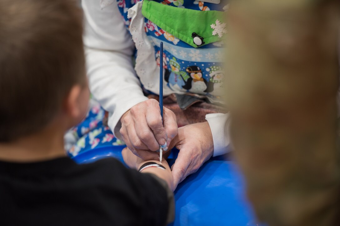A volunteer at the 25th Annual Winter Wonderland event paints on a child’s arm Dec. 7, 2018, at the Lied Activity Center in Bellevue, Nebraska. The event featured food, crafts, games, clowns, face painting, toys and family photos with Mr. and Mrs. Claus. (U.S. Air Force photo by Senior Airman Jacob Skovo)