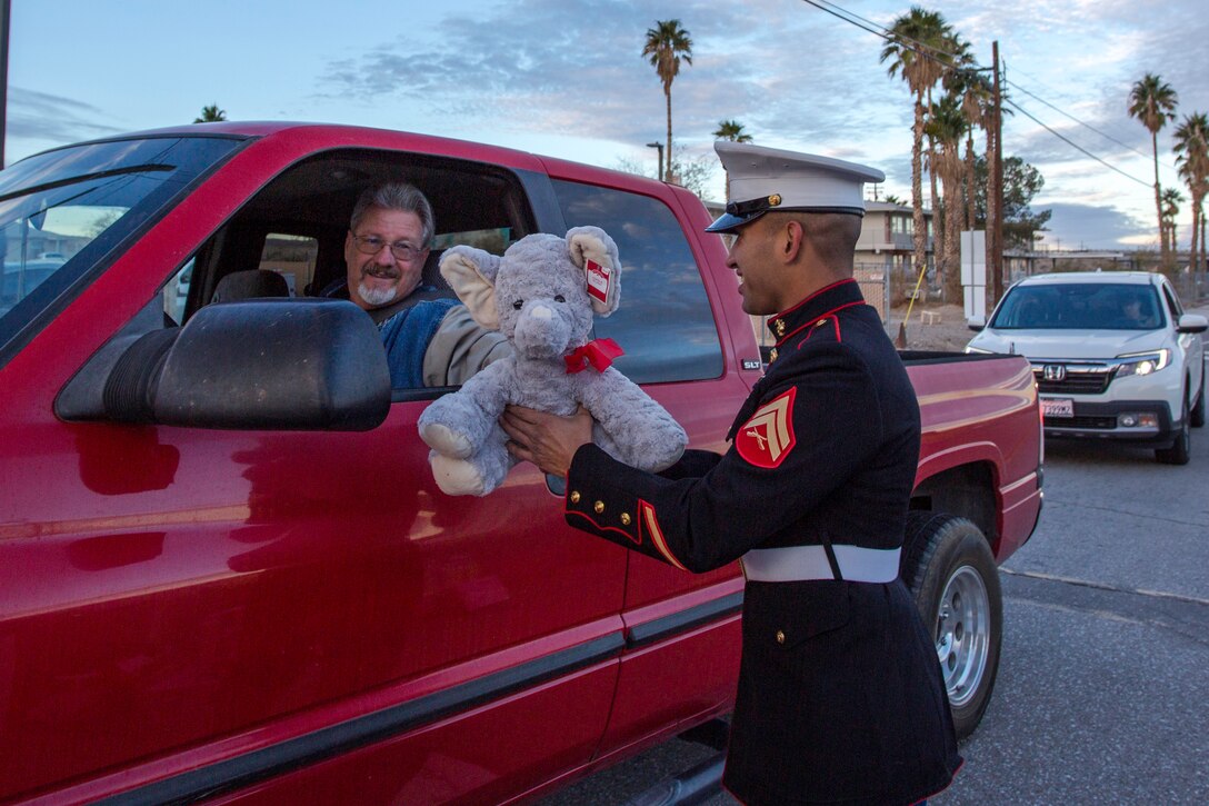 Corporal Manuel Ruiz, Fleet Support Division mechanic, receives a toy donation, in support of Toys for Tots, from Harrison Rogers at the front gate aboard Marine Corps Logistics Base Barstow, California, Dec. 4.
(U.S. Department of Defense Photo by Jack J. Adamyk)