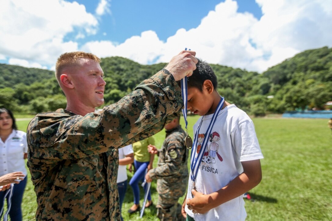 U.S. Marine Sgt. Andre Miller, with Special Purpose Marine Air-Ground Task Force - Southern Command, awards a student with Semillas de Esperenza Special Needs School for superior performance during the Special Needs Olympics in Flores, Guatemala, Sept. 28, 2018. The Marines of SPMAGTF-SC assisted the Guatemala Army’s First Brigade in hosting the event where students competed against friends, Marines, and Guatemalan soldiers to foster strong community relations. The Marines and sailors of SPMAGTF-SC are conducting security cooperation training and engineering projects alongside partner nation military forces in Central and South America. The unit is also on standby to provide humanitarian assistance and disaster relief in the event of a hurricane or other emergency in the region. (U.S. Marine Corps photo by Cpl. Jona Meme)