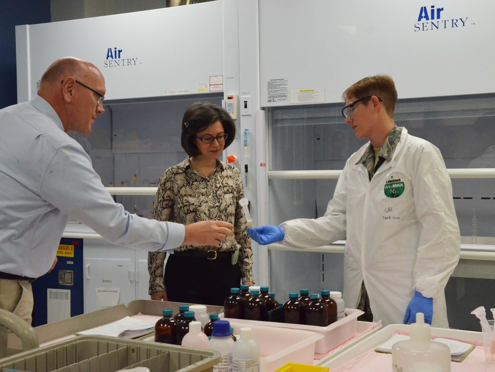 Airman 1st Class Cynthia A. Schroll (right), an Air Force E-3 with a doctorate in analytical chemistry at the Air Force Radiochemistry Laboratory, Patrick AFB, Fla., shows some of her work to Deputy Chief of Mission to International Organizations in Vienna Nicole Shampaine (center) along with senior scientist Dr. Bill Johnson (left). (U.S. Air Force photo by Susan A. Romano)