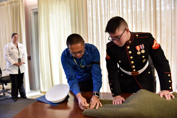 Benjamin Soria, Defense POW/MIA Accounting Agency (DPAA) lead evidence coordinator, helps U.S. Marine Corps Lance Cpl. Kenneth Henson secure the remains of U.S. Army Cpl. Albert E. Mills, who went missing in action during the Korean War, during a chain of custody event at Joint Base Pearl Harbor-Hickam, Hawaii, Nov. 9, 2018. Henson is the grand nephew-in-law of Mills and will escort his remains to Dallas. for burial. DPAA conducts global search, recovery and laboratory operations to provide the fullest possible accounting for our missing personnel to their families and the nation. (U.S. Air Force photo by Tech. Sgt. Kathrine Dodd)
