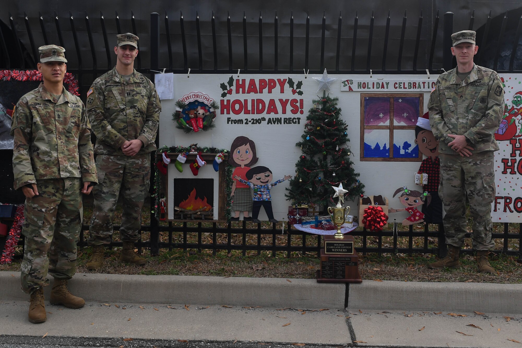 U.S Army Soldiers assigned to the 210th Aviation Regiment, 2nd Battalion, 128th Avn. Brigade stand in front of their winning holiday card at Joint Base Langley-Eustis, Virginia, Dec. 13, 2018. The winning units received gift cards that can be used towards morale events. (U.S. Air Force photo by Senior Airman Derek Seifert)