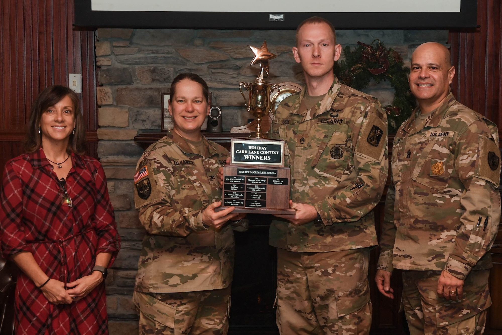 U.S. Army Col. Jennifer Walkawicz, 733rd Mission Support Group commander, and Command Sgt. Maj. Eric Vidal, 733rd MSG command sergeant major, presents the Holiday Card Lane contest trophy to the 210th Aviation Regiment, 2nd Battalion, 128th Avn. Brigade at Joint Base Langley-Eustis, Virginia, Dec. 13, 2018. The Regional Memorial Chapel was awarded second place and the Headquarters and Headquarters Company, 7th Transportation Brigade (Expeditionary) came in third place. (U.S. Air Force photo by Senior Airman Derek Seifert)