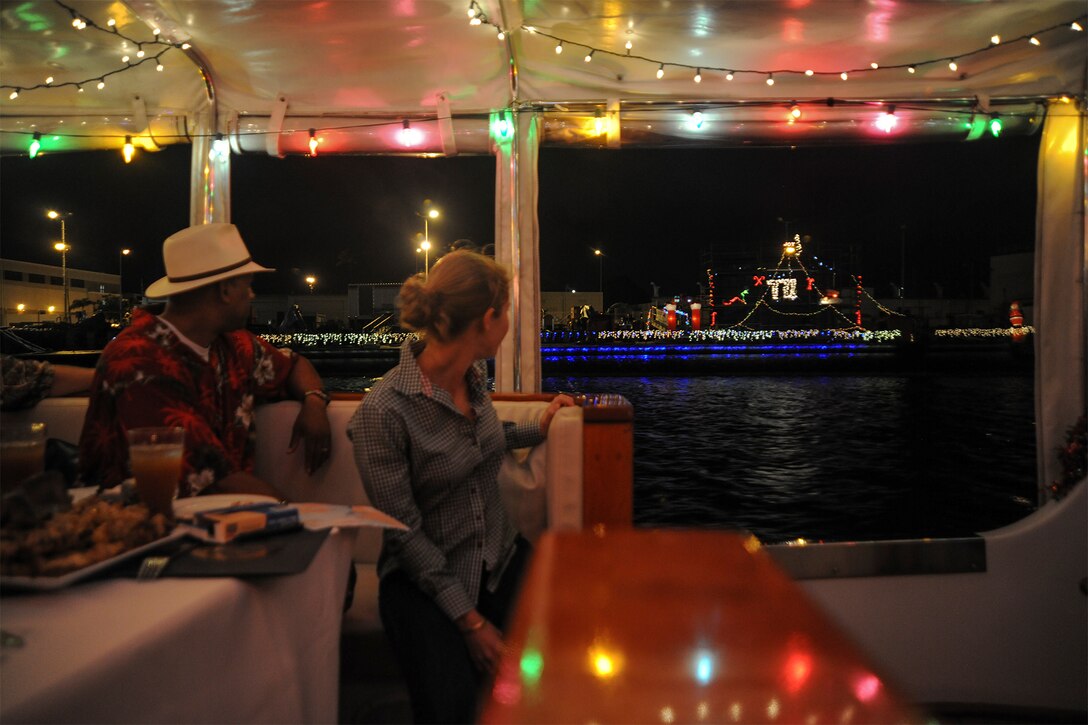 Diners look out at a ship decorated with Christmas lights.