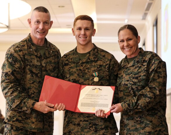 U.S. Marine Corps Brig. Gen. Stephen M. Neary, commanding general of 2nd Marine Expeditionary Brigade, and Sgt. Maj. Joy M. Kitashima of II Marine Expeditionary Force Information Group, presents a Navy and Marine Corps Achievement Medal to Lance Cpl. Matthew Ellis, a 2nd MEB intelligence specialist, at Camp Lejeune, N.C., Dec. 11, 2018. Ellis received the award for his exemplary performance while supporting the unit during Exercise Trident Juncture 18 in Norway. The award is earned by exemplifying superior performance outside one’s designated military occupational specialty. (U.S. Marine Corps photo by Cpl. Patrick Osino)