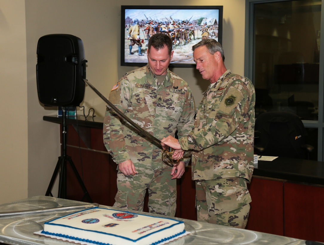 U.S. Air Force Maj. Gen. Jon K. Mott, , U.S. Central Command's director of exercises and training (right) and U.S. Army Staff Sgt. Michael Tousey (left) prepare to cut the cake to honor the National Guard's 382nd birthday at U.S. Central Command headquarters, Dec. 13, 2018. The National Guard administered State Partnership Program, established in 1993, is a key component of CENTCOM's mission and the National Defense Strategy. (U.S. Central Command Public Affairs photo by Tom Gagnier)