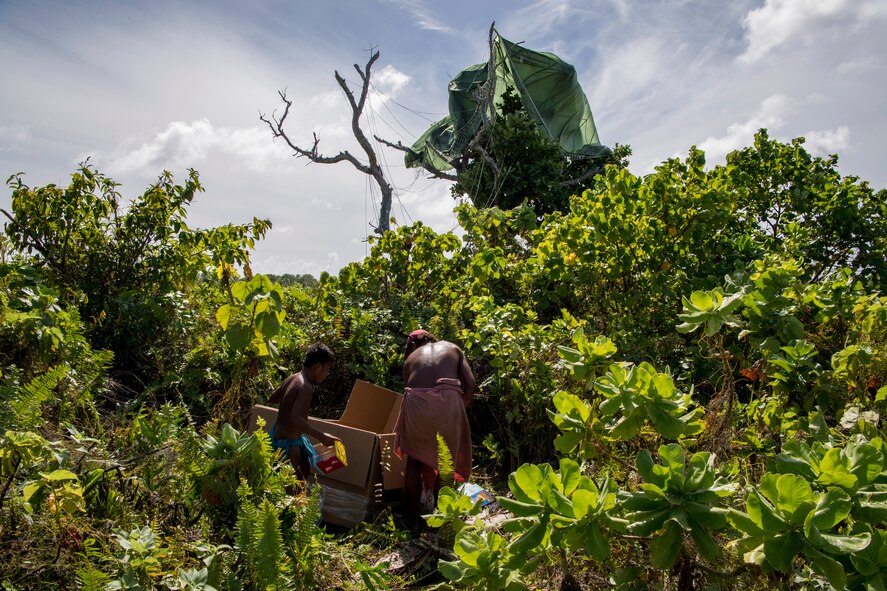 A father and child unload a low-cost low-altitude bundle of humanitarian supplies