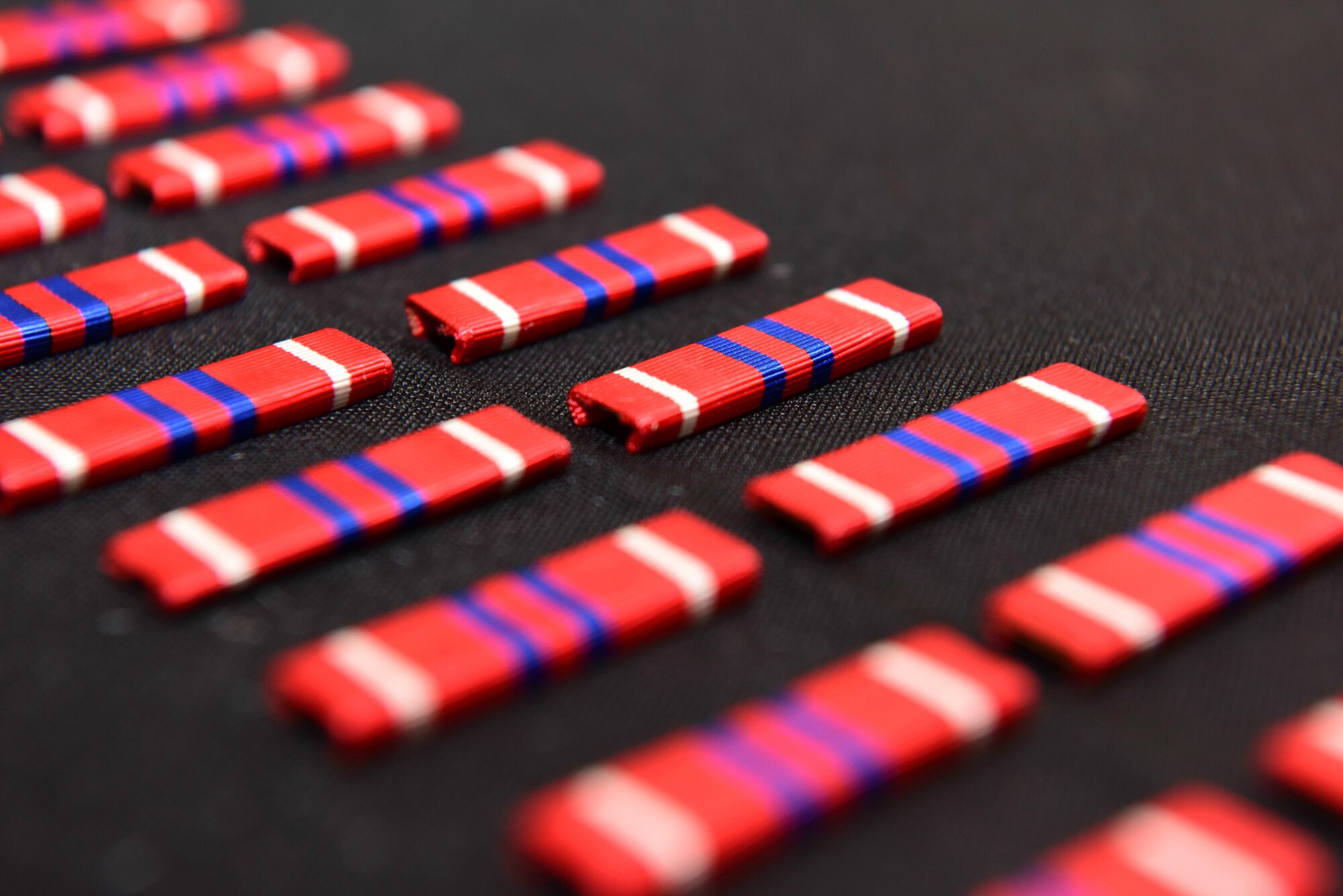 Rows of Airman Leadership School ribbons lay on a table during an ALS graduation ceremony.