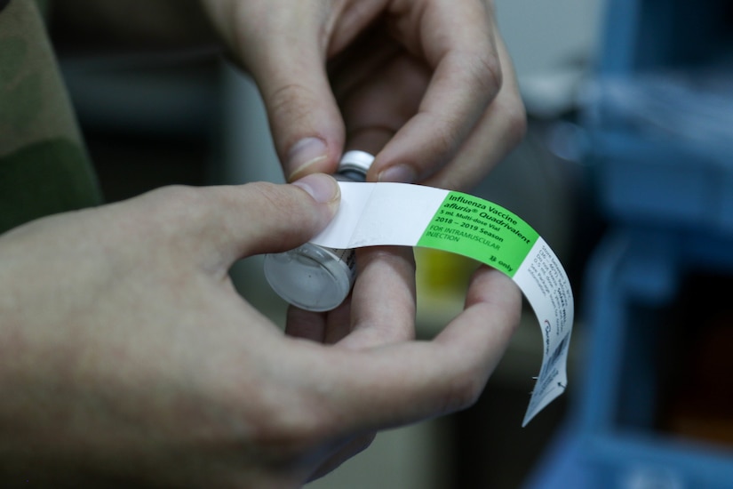 U.S. Army Pfc. Megan Wilbanks, a healthcare specialist with Headquarters and Headquarters Company, 35th Combat Aviation Brigade, a Missouri Army National Guard unit headquartered in Sedalia, Missouri, unravels the label on an influenza vaccination bottle at the 935th Aviation Support Battalion combined aid station, Camp Buehring, Kuwait, Dec. 10, 2018.  The CAS provided level-two medical care to U.S. Soldiers assigned to the 35th CAB.