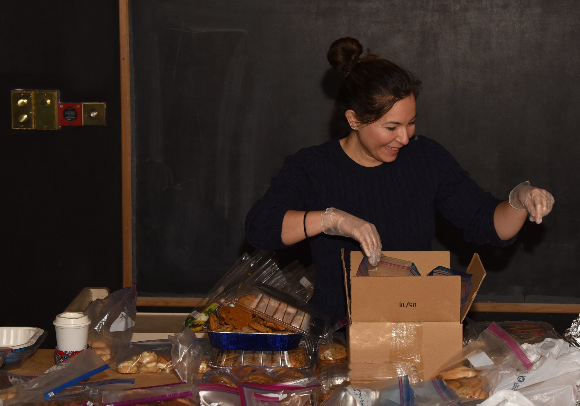 Soris Cox, a Liberty Spouses Association member, packs cookies for the Airman Cookie Drive at Royal Air Force Lakenheath, England, Dec. 12, 2018. For more than nine years, the Liberty Spouses and First Sergeants associations have been helping Lakenheath Airmen feel a little more at home during the holidays through the cookie drive. (U.S. Air Force photo by Airman 1st Class Madeline Herzog)