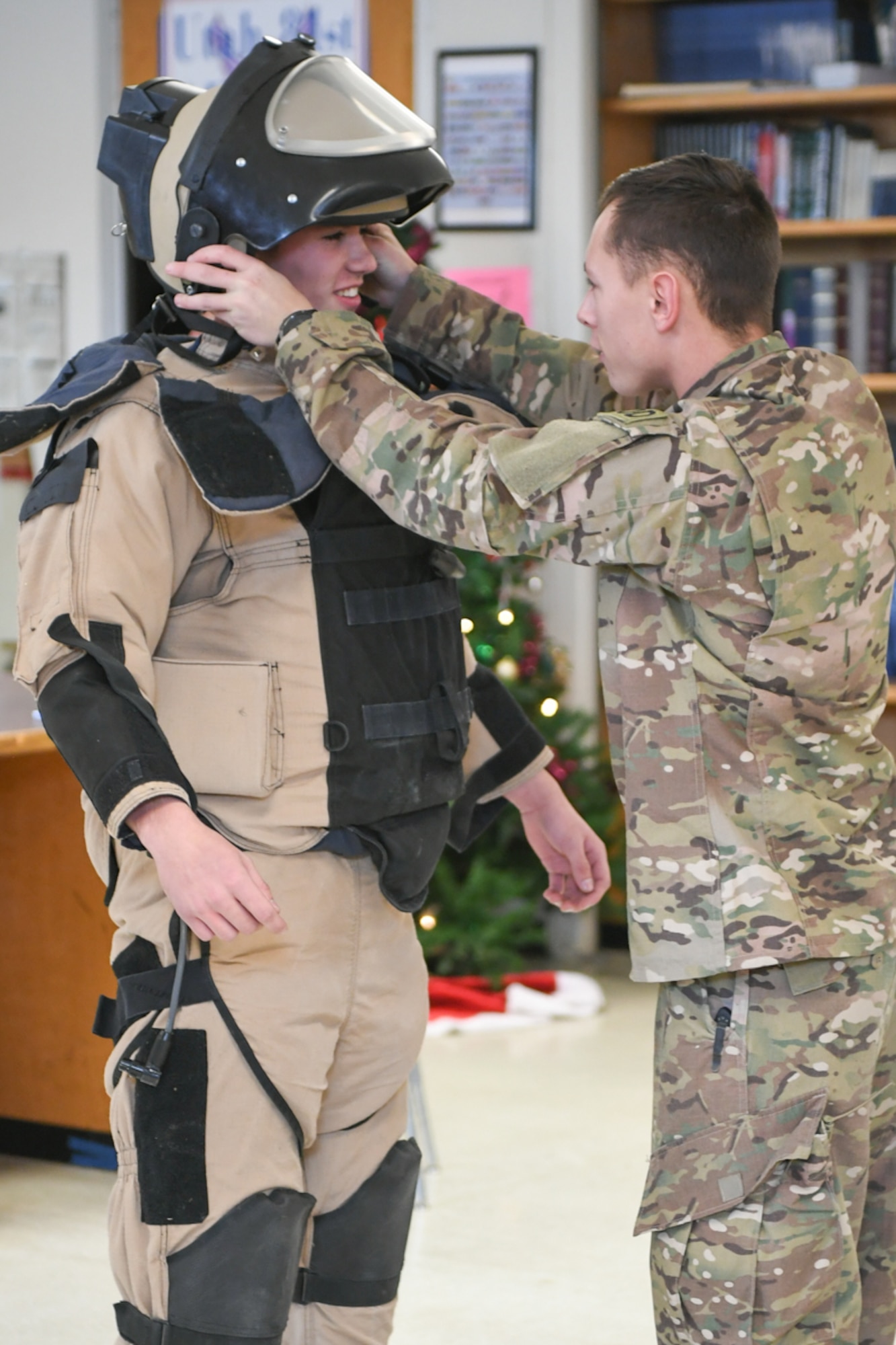 Airman 1st Class Zachary Hallett, 775th Explosive Ordnance Flight, helps high school senior Calvin Kinnersley put on a bomb suit worn by Air Force EOD technicians. Technical Sgt. Andrew Mistkowski (back), 419th Fighter Wing recruiter, invited Hill Air Force Base EOD technicians to meet with Junior Reserve Officer Training Corps students at Clearfield High School in Clearfield, Utah, Dec. 12, 2018. (U.S. Air Force photo by Cynthia Griggs)