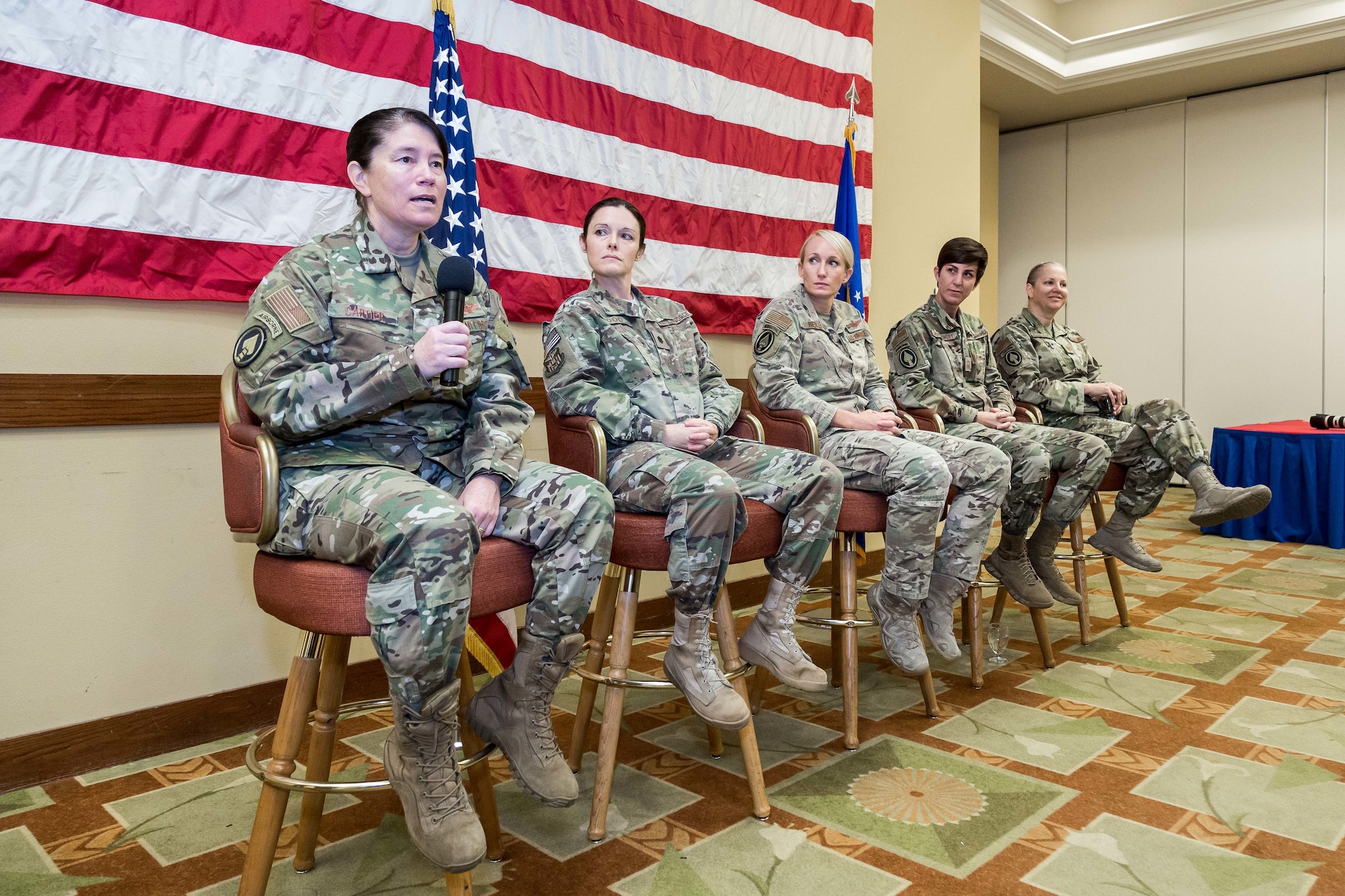 Five women speaking at a conference