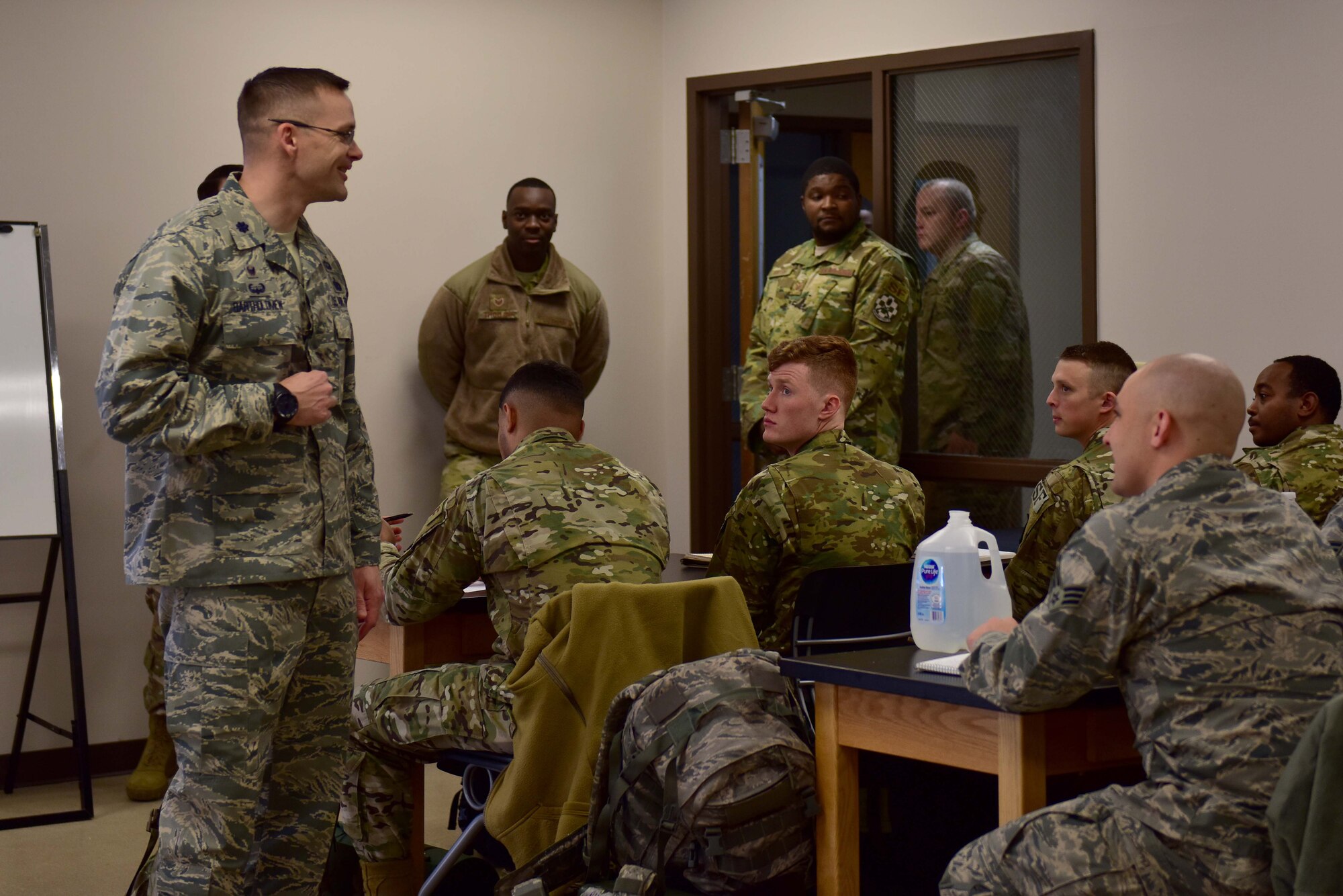 A man wearing the Airman Battle Uniform speaks to other people wearing the ABU and operational camouflage pattern uniform.