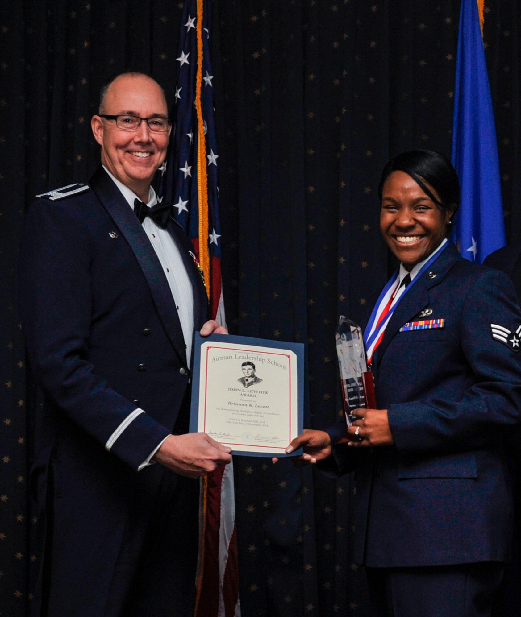 Senior Airman Brianna Lovett, 377th Logistics Readiness Squadron fire truck maintenance apprentice, is awarded the John L. Levitow Award by 377th Air Base Wing Commander Col. Richard Gibbs during the graduation of Kirtland’s Airman Leadership School Class 19-2 here Dec. 13. The John L. Levitow Award is the highest award given during enlisted professional military education courses. (U.S. Air Force photo by Staff Sgt. Dylan Nuckolls)