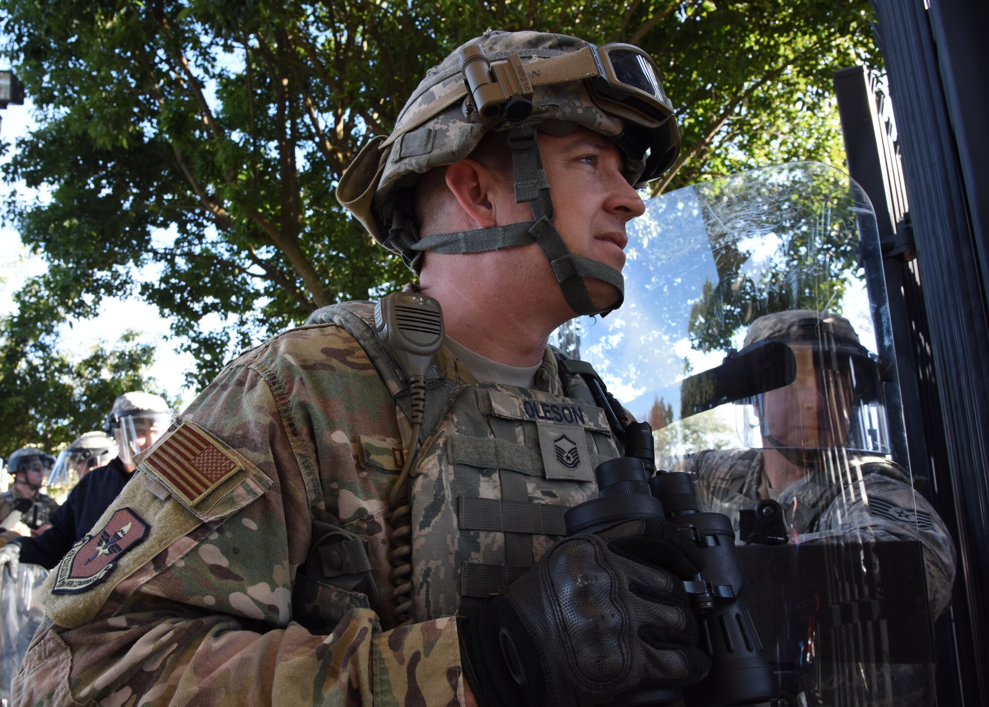 U.S. Air Force Master Sgt. Matthew Oleson, 81st Security Forces Squadron operations NCO in charge, observes the protesting crowd prior to assembling his riot team during the 81st SFS protest drill at Keesler Air Force Base, Mississippi, Dec. 12, 2018. The scenario included peaceful protestors expressing their first amendment right that further escalated to a riot when they felt they weren't being heard. The drill, which was a joint effort with the Biloxi Police Department, was conducted to control or prohibit demonstrations and protests. (U.S. Air Force photo by Kemberly Groue)