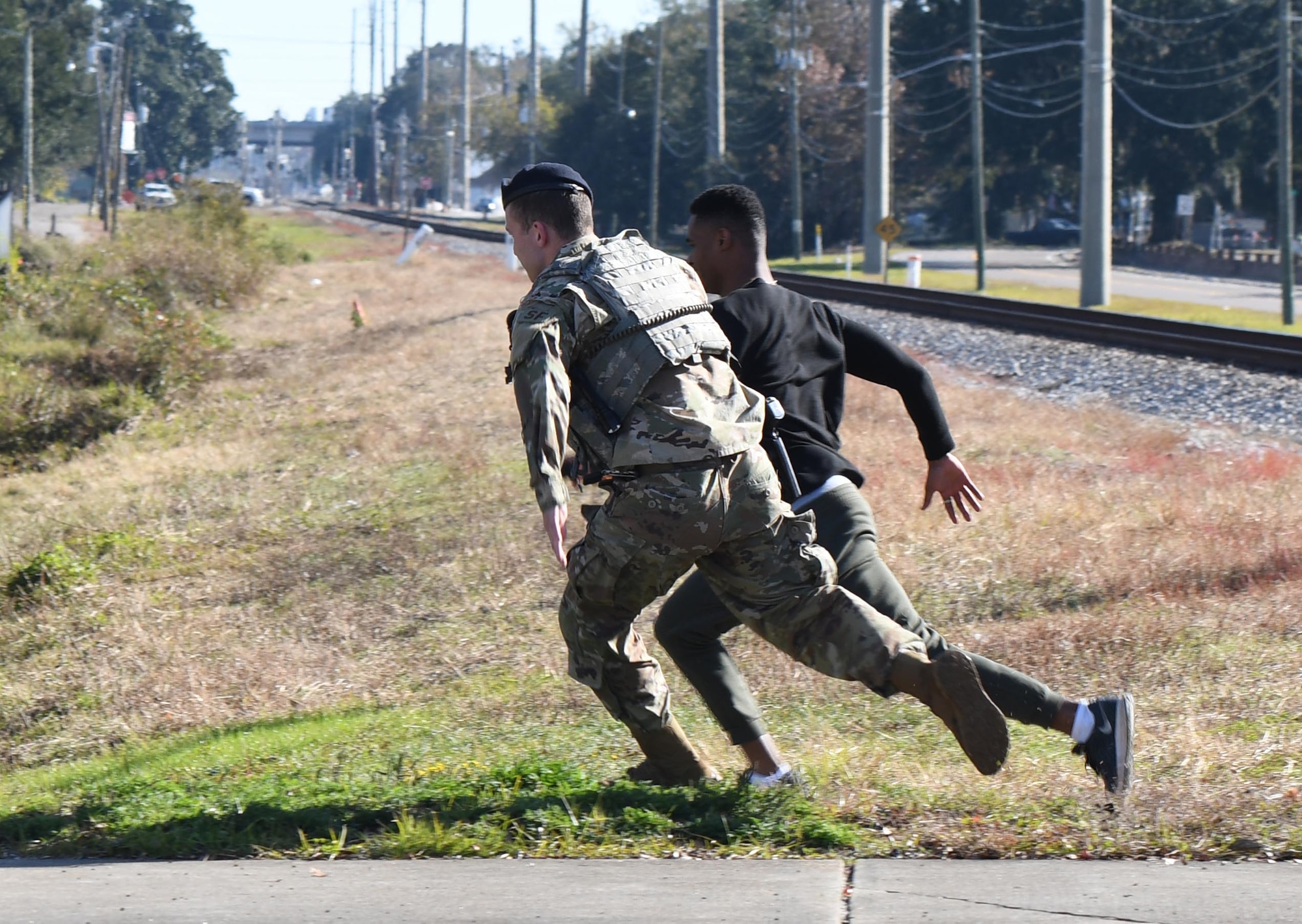 U.S. Air Force Senior Airman Matthew Brooks, 81st Security Forces Squadron military working dog handler, pursues Airman Jair Semexant, 81st Medical Support Squadron logistics technician, who is portraying a "protestor" attempting to breach the installation perimeter during the 81st SFS protest drill at Keesler Air Force Base, Mississippi, Dec. 12, 2018. The scenario included peaceful protestors expressing their first amendment right that further escalated to a riot when they felt they weren't being heard. The drill, which was a joint effort with the Biloxi Police Department, was conducted to control or prohibit demonstrations and protests. (U.S. Air Force photo by Kemberly Groue)