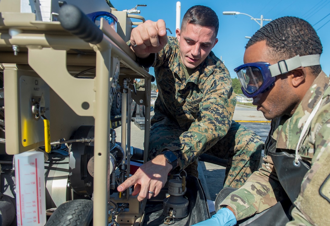 Marine Corps Staff Sgt. Clayton Leatherwood, a laboratory course chief at the Marine Corps Detachment Fort Lee, Va., discusses operating procedures for the Expeditionary Mobile Fuel Additization Capability with Army Sgt. Jarrod Stegall, a petroleum and water specialist at Ft. Lee, Va., during a test at the Charleston Defense Fuel Supply Point Dec. 6, 2018.