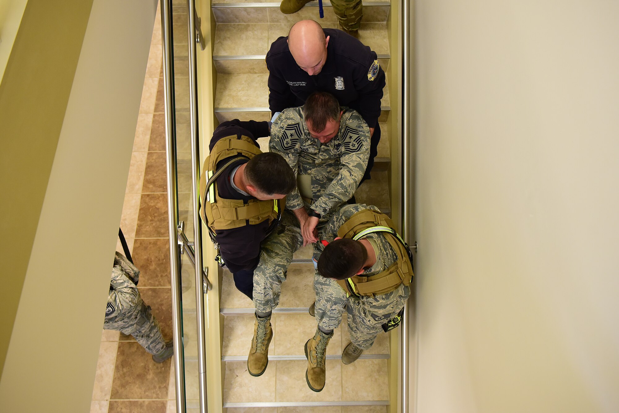 Chief Master Sgt. Stephen Cornelius, 4th Fighter Wing Command Chief, acts as a simulated victim and is carried down the stairs by three 4th Civil Engineer Squadron firefighters during a planned active shooter exercise Dec. 12, 2018, at Seymour Johnson Air Force Base, North Carolina. During the exercise, unsuspecting individuals are labeled injured or deceased to help create a more realistic exercise. (U.S. Air Force photo by Senior Airman Kenneth Boyton)